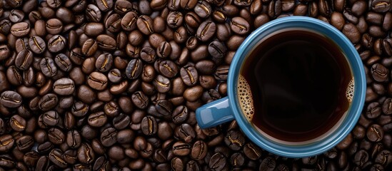 Aufkleber - Top down view of a black coffee filled blue cup set against a background of freshly roasted coffee beans creating a copy space image