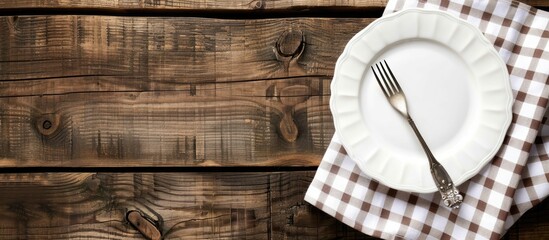Leinwandbilder - A white plate and fork placed on a rustic wooden table with a checkered tablecloth and ample copy space for text or images