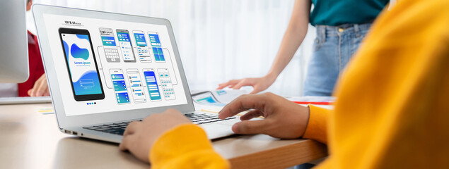 Panorama banner of startup UX developer or company employee design user interface or UI prototype for mobile application or website software with software display on laptop monitor in office. Synergic