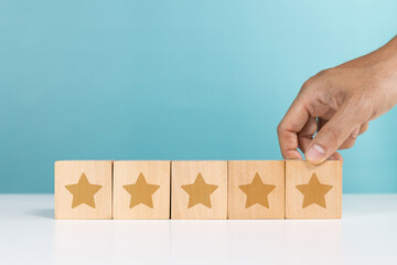 Service rating, positive feedback, satisfaction concept. A man holding wooden cube with star icon give five star rating indicating satisfaction level of service users