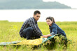 © freebird7977 - Friend helping installing  tent camping outdoor near river and meadow.  Group young people family travel adventure destination leisure in vacations holiday.  Travel Concept