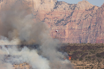 Kolob Terrace Road Utah, USA July 27th 2024 Wildland firefighters approach a fire burning on a cliffside from the air in preparation to drop fire retardant from a bomber flying through the smoky haze.