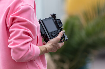 A girl holds a SLR camera in her hands. Close-up