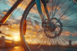 A close-up shot of a bicycle wheel against a beautiful sunset backdrop
