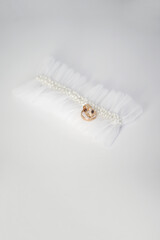 Canvas Print - Wedding rings and garter on the leg of the bride on a white background.