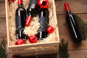 Wall Mural - Wooden crate with bottles of wine, fir twigs and red Christmas balls on table, above view