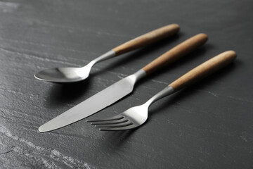 Wall Mural - Stylish cutlery. Fork, spoon and knife on black table