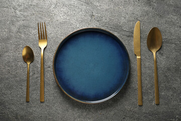 Wall Mural - Stylish golden cutlery and plate on grey table, flat lay