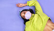 © peopleimages.com - Woman, face mask and safety in studio for danger, allergy and virus with retro fashion. Gen z, social distancing and memory on floor for outfit, style and mockup space for risk by purple background