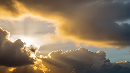 Wall Mural - The sun breaking through the clouds after a rainstorm, casting a golden, warm glow on the remaining gray and white clouds.