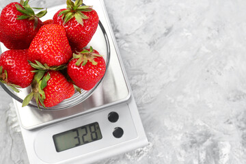 Wall Mural - Kitchen scale with bowl of strawberries on grey textured table, top view. Space for text