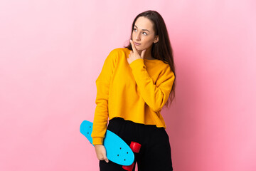 Wall Mural - Young hispanic woman over isolated pink background with a skate and looking lateral