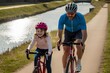 © NASSRI - Deux cyclistes (un homme et une fillette) pratiquant le cyclotourisme sur piste cyclable au bord du canal de Bourgogne, à Dijon en Côte d’Or (France) portant casque en nature en course avec fille