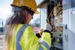 © zphoto83 - Female electrician working on electrical control panels at a construction site on a sunny day