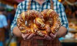 © peppastocker - A man in lederhosen holding a large pretzel at the Oktoberfest festival.