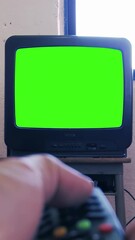 Wall Mural - hand using remote to turn on vintage tv with green chroma key screen. you can replace green screen w