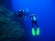 © blue-sea.cz - Group of scuba divers exploring underwater landscape and wall. Divers in the water, yellow fins. Marine life in the ocean, tourist exploration. Photo from adventure dive. Marine life and tourism.
