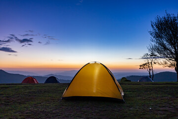 Wall Mural - Adventurer tents during overnight camping site at the beautiful scenic sunset view point over layer of mountain for outdoor adventure vacation travel