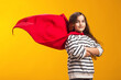 © Aleksej - Child girl in red cloak plays superhero over yellow background. Education and success concept.