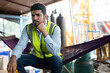 © Supachai - Construction crane worker wearing a safety vest sits pensively in hammock, taking a break at work site.