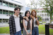 © amnaj - Three cheerful asian students standing together on a campus lawn, enjoying their time at university