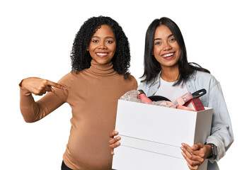 Latin women couple moving, one pregnant  person pointing by hand to a shirt copy space, proud and confident