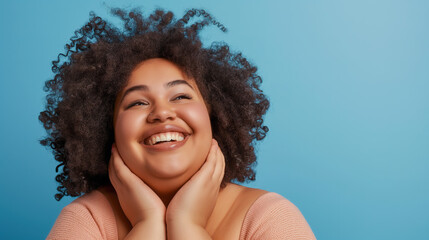  cheerful plus-size woman with natural hair smiling and touching her face isolated on a blue background