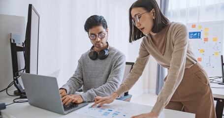 Young adult Asian male, female software developer coding program on desktop computer. Man, woman work from home, remote working, freelance programmer job, smart digital nomad lifestyle concept