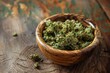 © anatolir - Closeup of quality dried cannabis flowers in a rustic wooden bowl on a textured tabletop