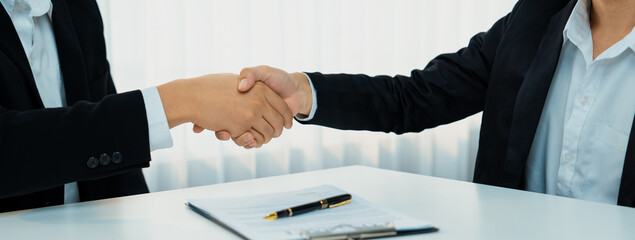 Wall Mural - Two business executive shake hand in boardroom, sealing agreement merging two company. Handshake symbolize business partnership and cooperation. Corporate acquisition and merger concept. Shrewd