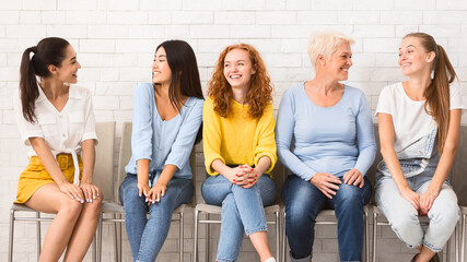 Wall Mural - Female Networking Group. Cheerful Diverse Women Of Different Age Talking Sitting On Chairs Indoor. Panorama