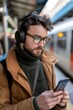 © spyrakot - Professional Learning via Mobile App During Commute with Headphones in Vibrant Train Station Setting