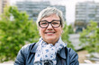 © Xavier Lorenzo - Smiling portrait of senior woman looking at camera outdoor. Head shot of 60 year old woman over urban background.