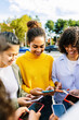 © Xavier Lorenzo - Diverse group of young girls using smart mobile phone at city street. Technology and youth lifestyle concept
