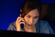 © InfiniteFlow - Young beautiful Asian creative woman calling on phone to customer or coworker informing strategy marketing creator plan while searching market analysis on pc at neon modern office at night. Stratagem.