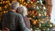 © Jafree - Elderly couple embracing in front of a decorated Christmas tree. Concept of senior love, holiday season, festive celebration, family togetherness