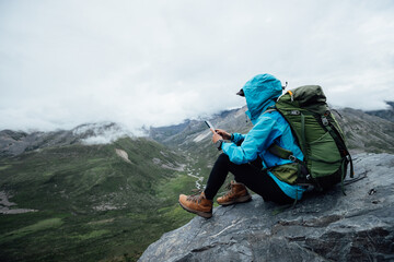 Hiking woman taking photo with samrt phone on high altitude mountain top