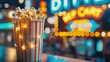 © busro - Close-up of a popcorn bucket on a neon-lit cinema concession stand, with a blurred background of glowing signs