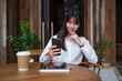 © wattana - Beautiful young businesswoman using mobile phone while sitting in modern cafe. Business communication and lifestyle concept.