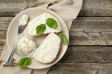 Wall Mural - Delicious sandwiches with cream cheese and basil leaves on wooden table, top view. Space for text