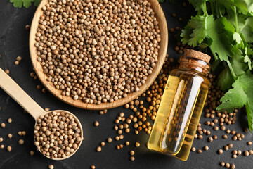 Canvas Print - Coriander essential oil, seeds and green leaves on black table, top view