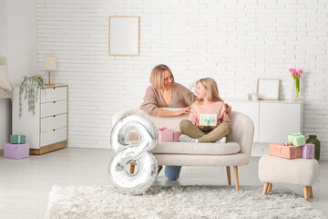 Wall Mural - Beautiful young woman and her cute little daughter with gift boxes and air balloon in shape of figure 8 in living room