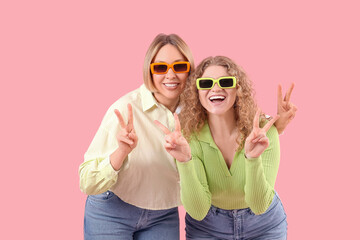 Sticker - Beautiful happy women in stylish jeans showing victory gesture on pink background