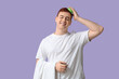 © Pixel-Shot - Young man using hair scalp massager on lilac background