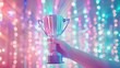 © mashimara - Hand holding silver trophy with vibrant, colorful bokeh lights in the background, creating a lively and celebratory atmosphere.