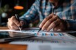 © momostudio - Close-up of a Person's Hand Pointing at a Graph with a Pen