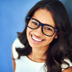 Wall Mural - Portrait, confidence and woman with glasses in studio for optometry, vision or prescription lens on blue background. Refraction, wellness and business person with for spectacles, eyewear or top view