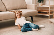 © SHOTPRIME STUDIO - Little girl playing with colorful building blocks on a cozy living room floor in front of a modern gray couch