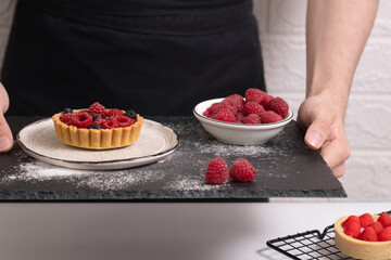 Man decorate sweet dessert. Male baker add berry decoration. Guy cook little tasty pie. Confectionery pastry.