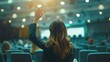 © improvee design - Woman raises her hand to ask a question during a conference. The image captures the moment of interaction and engagement during a formal presentation.